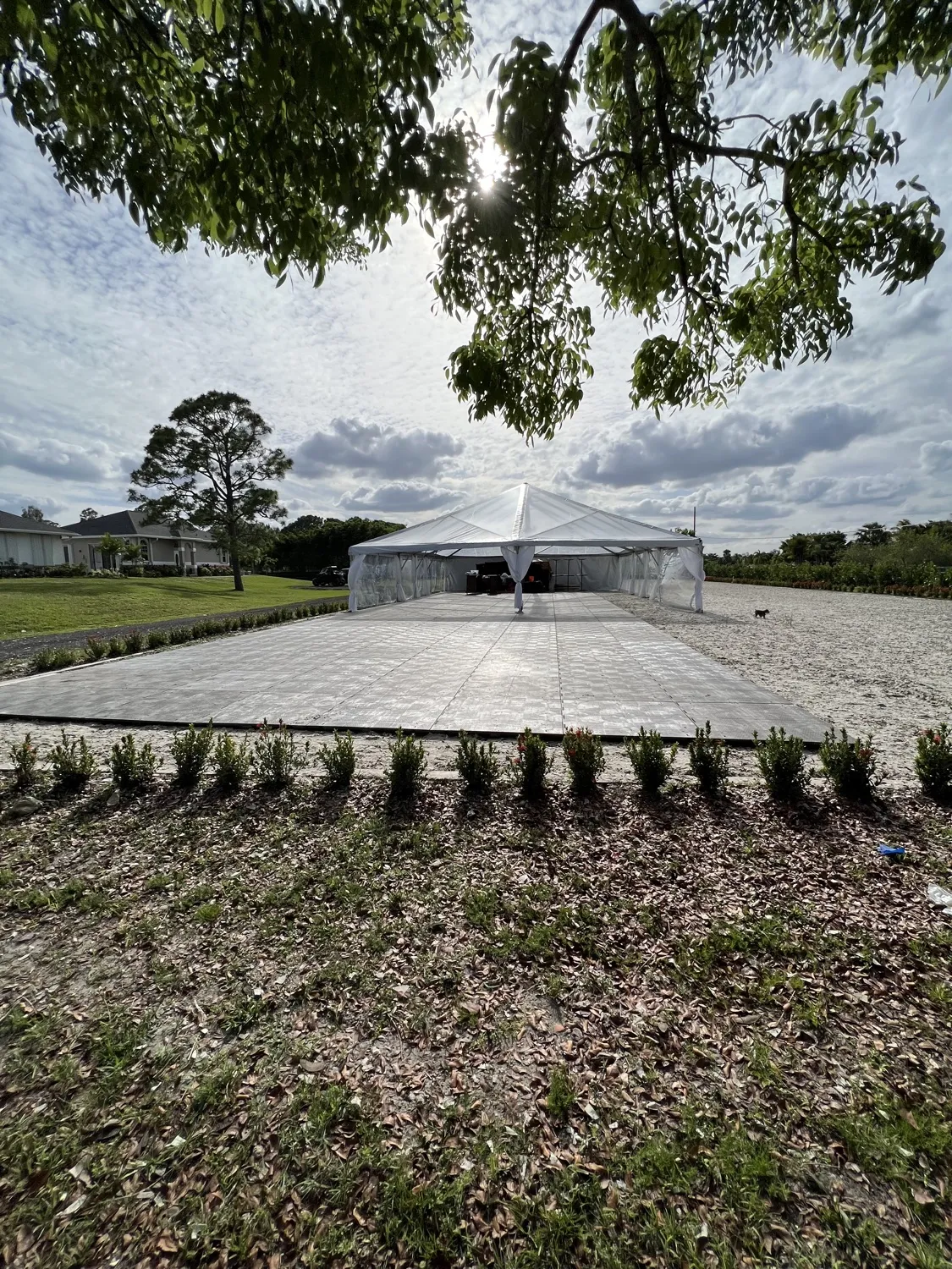 An event tent on bare ground and a temporary floor before the install