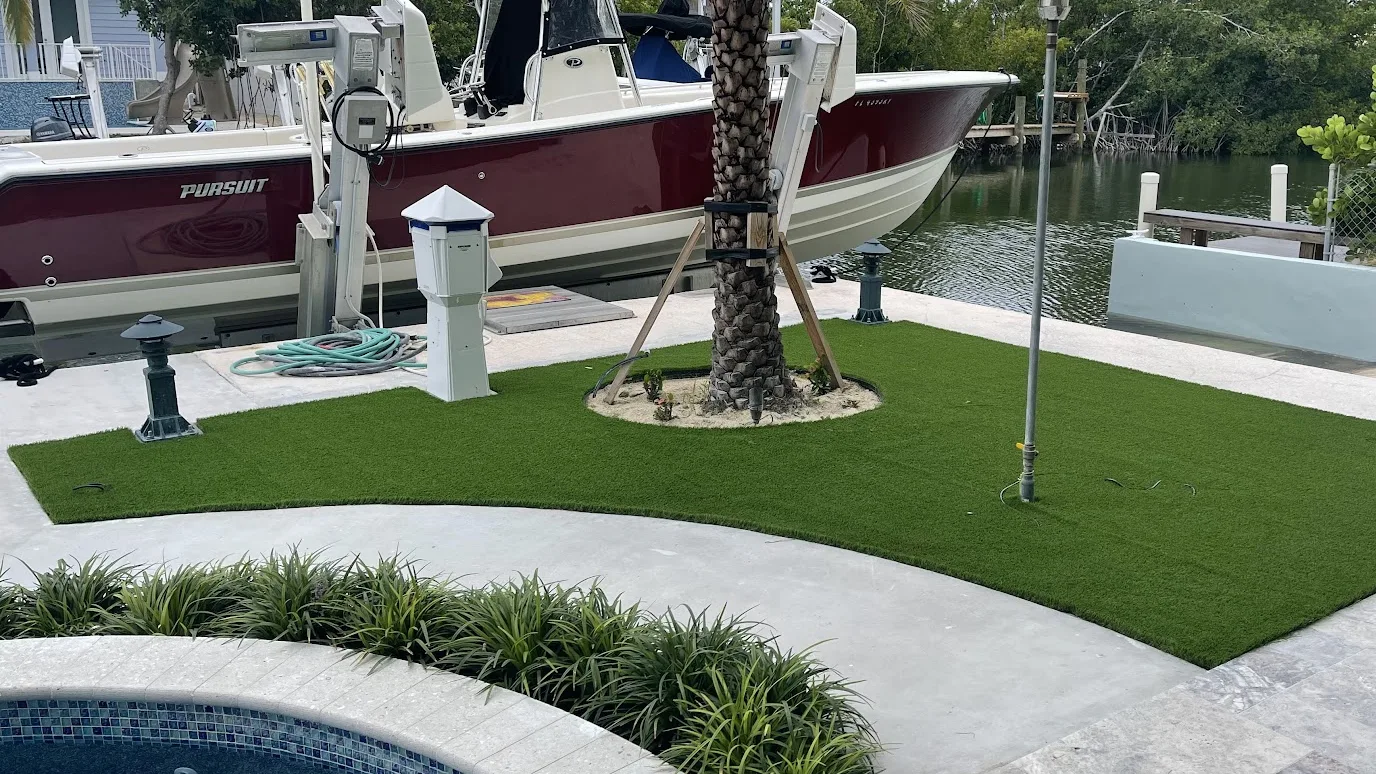 The same yard after: green turf around the palm, between the dock and the pool