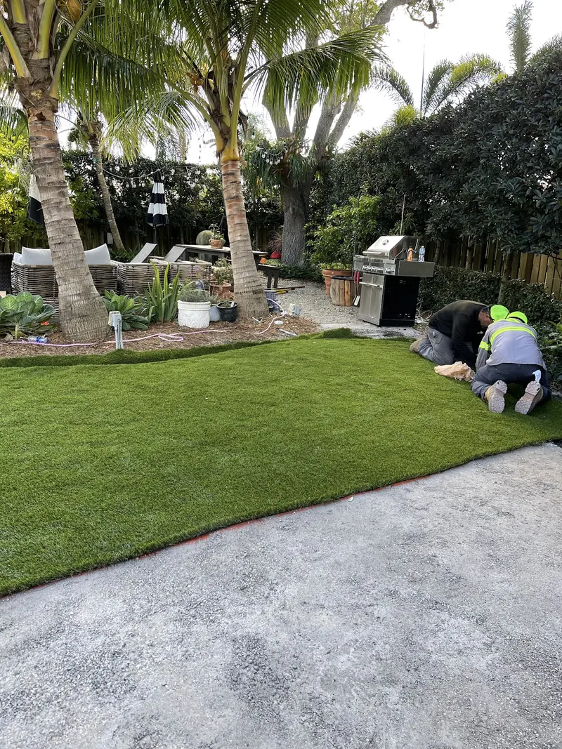 Crew laying a turf lawn beside a stamped concrete patio