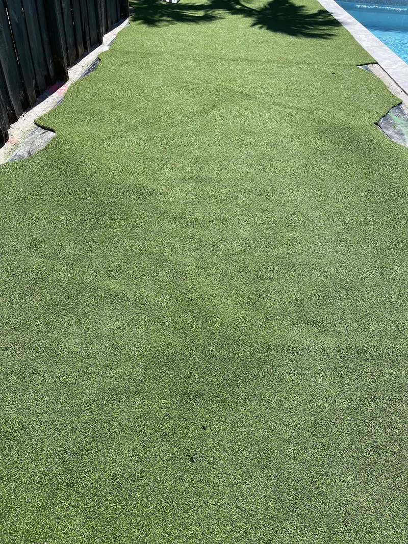 A freshly laid turf section with clean edges, running along a pool