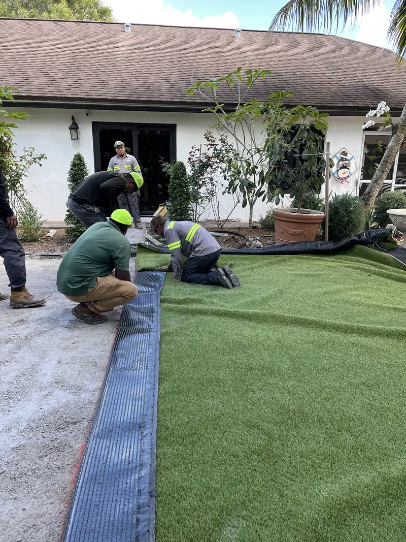 AJ Turf crew seaming and laying turf in front of a home