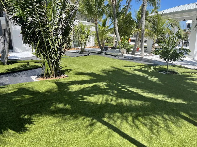 Turf rolled out across a backyard with palms, the install coming together