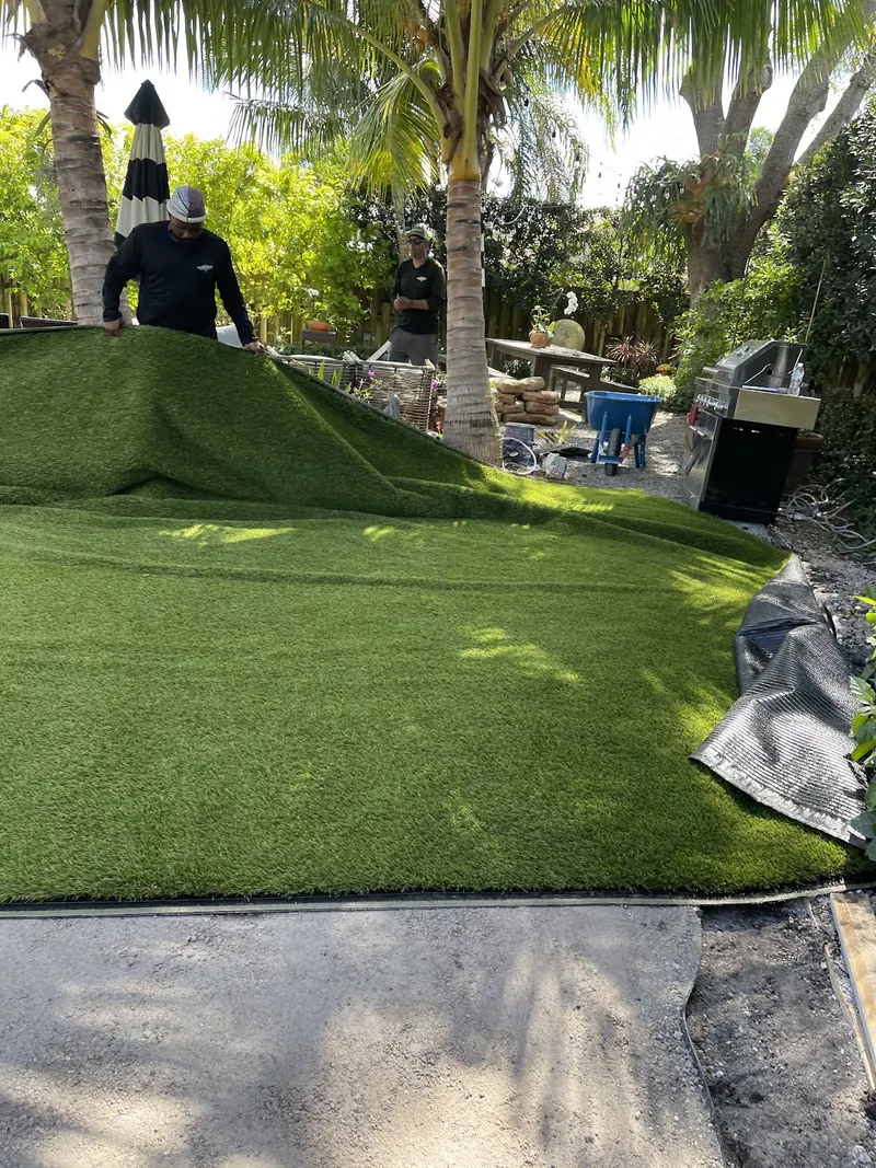 Crew unrolling a turf roll across a prepared backyard