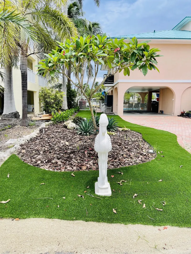 Curved turf front yard around a planted bed with a statue