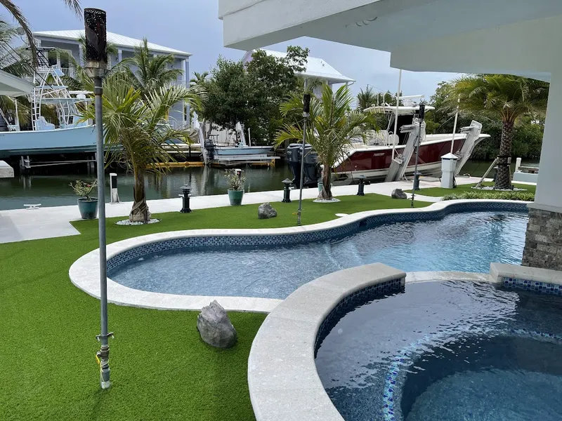 Turf surrounding a curved pool and spa on a canal-front lot