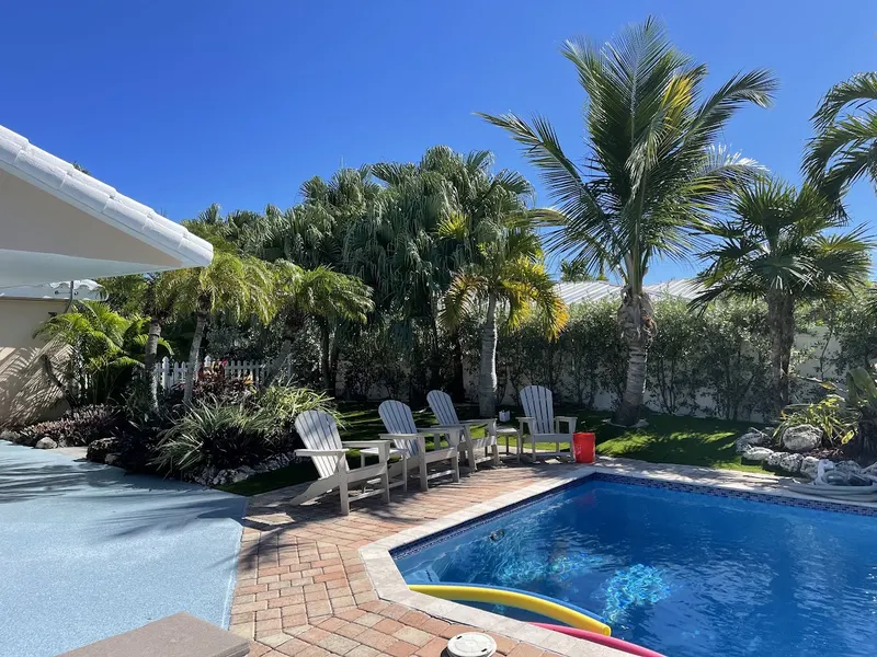 Turf lawn behind a pool with Adirondack chairs