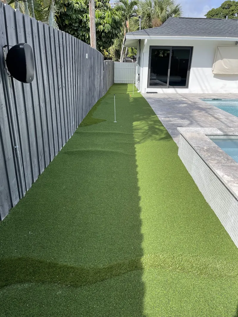 Turf putting strip running beside a pool and fence