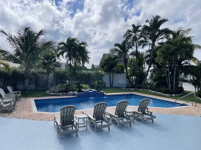 Turf lawn behind a pool lined with lounge chairs
