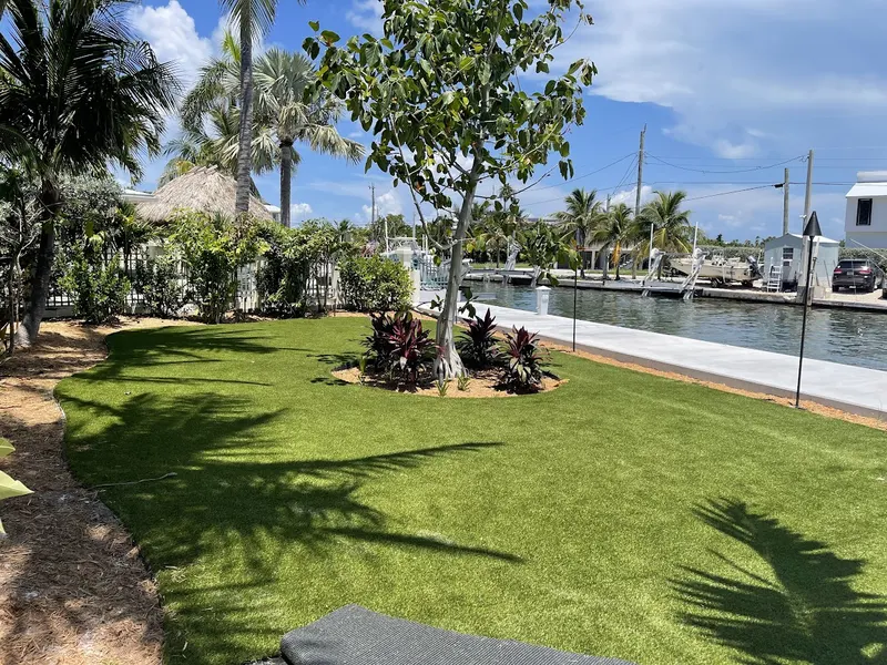 Turf lawn with a planted bed beside a canal and docks