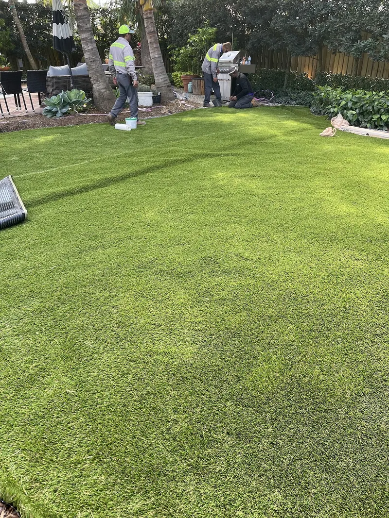 Freshly installed turf lawn with the crew finishing up