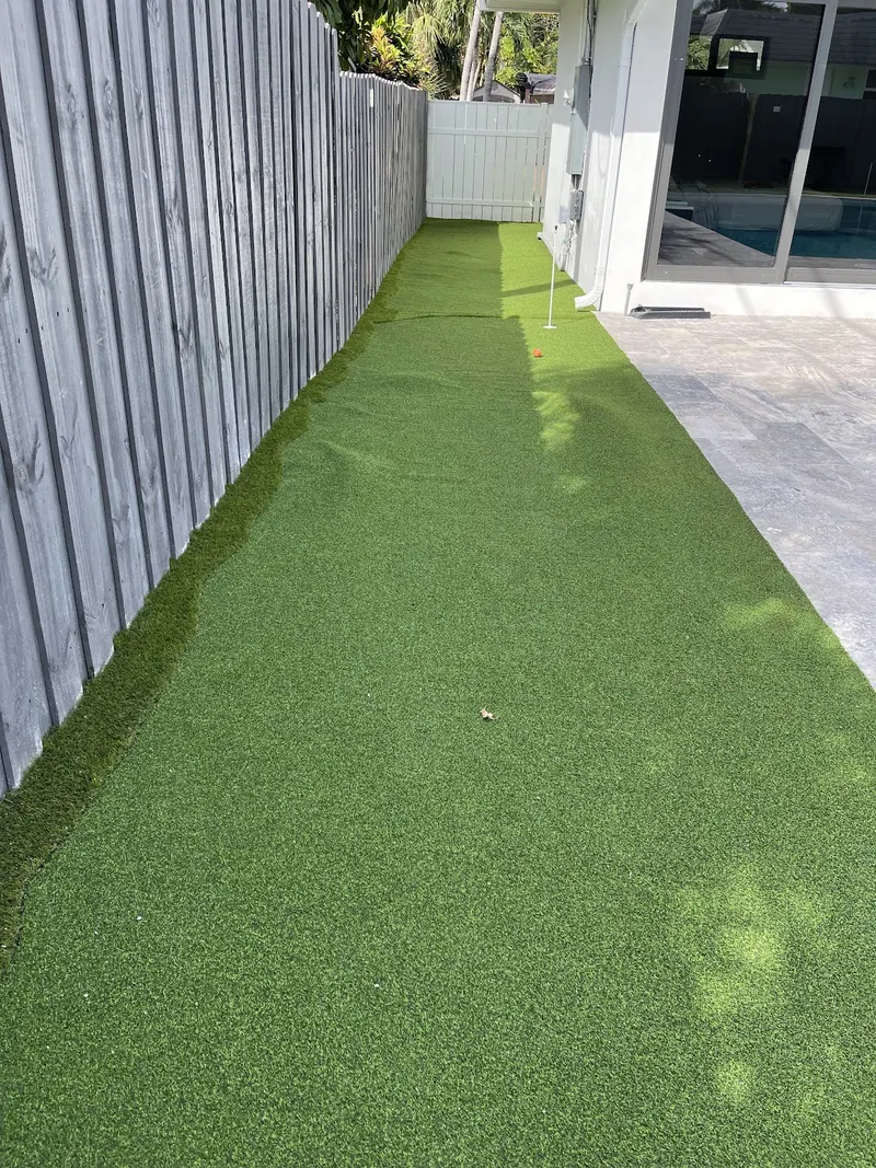 Long turf run beside a fence and pool deck