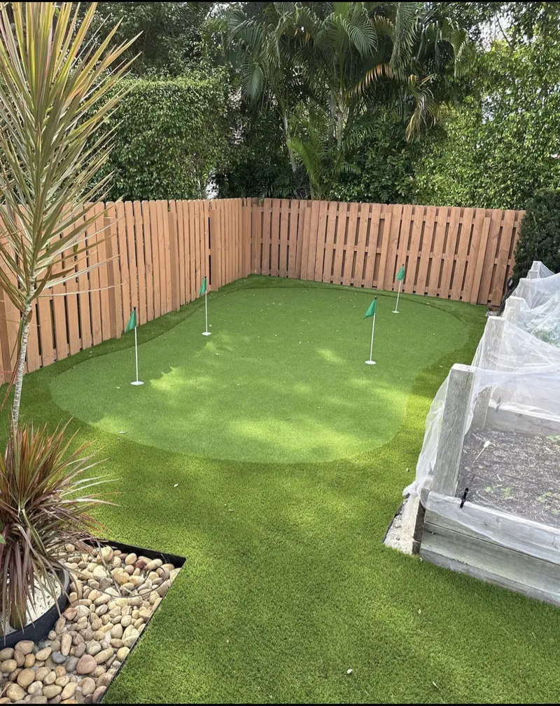 Fenced backyard putting green with three flags
