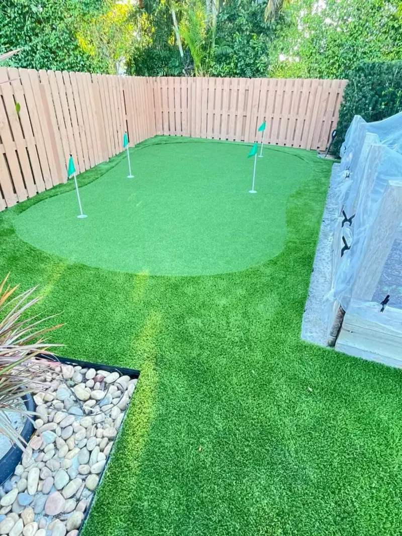 Putting green with fringe and four flags in a fenced yard