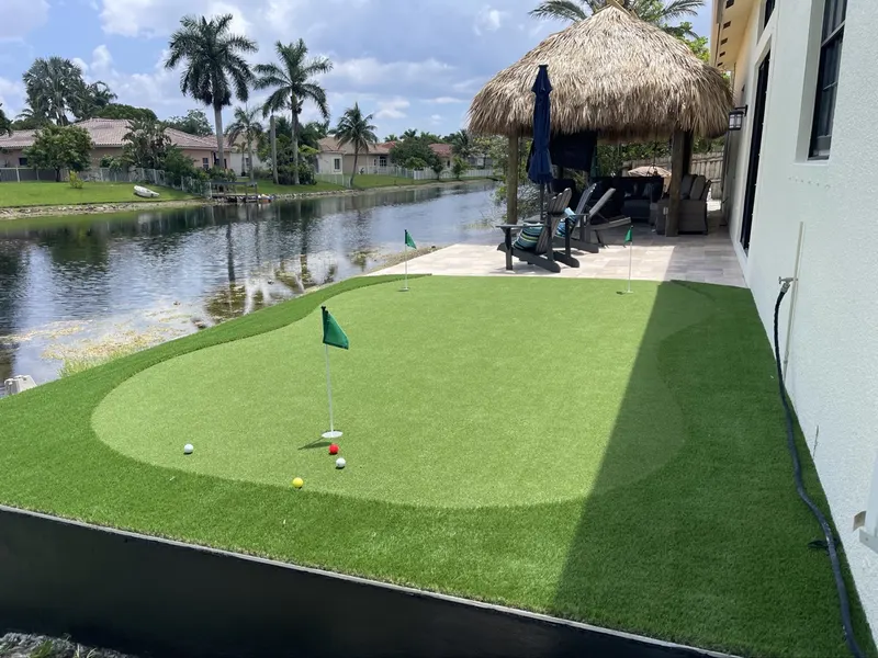 Putting green with fringe beside a tiki hut on the water