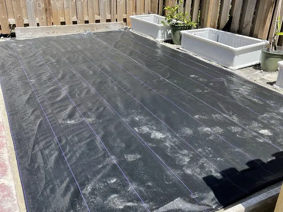 Black weed barrier covering a whole fenced pad